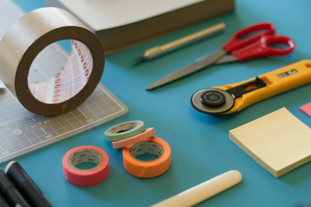 Scissors, tape, pencils and paper on a craft table