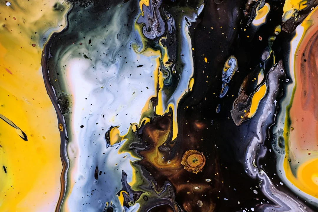 A close view of fluid paint in yellow, black and white